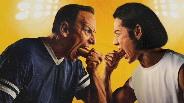 The picture shows two men eating hot dogs. 